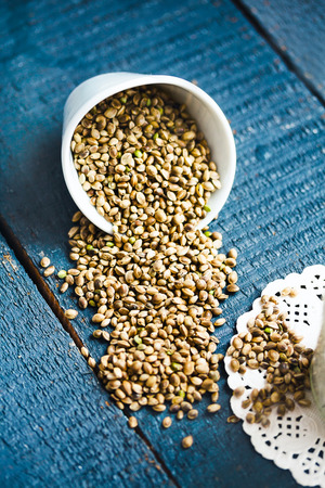 Whole hemp seeds in a white bowl, placer, blue background, health proteinの写真素材