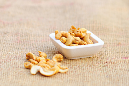Raw cashews in small cup on sackcloth の写真素材