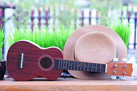 Brown Ukulele with lovely hat placed on wooden