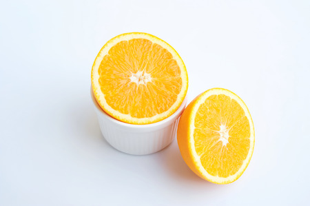 Orange fruit sliced and in cup on white backgroundの写真素材