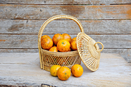 Orange in a basket on wooden backgroundの写真素材