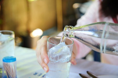 Pouring ice water in the glassの写真素材