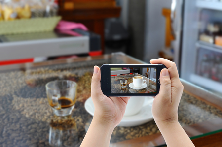 hot coffee cappuccino  in cup on mobile smart phoneの写真素材