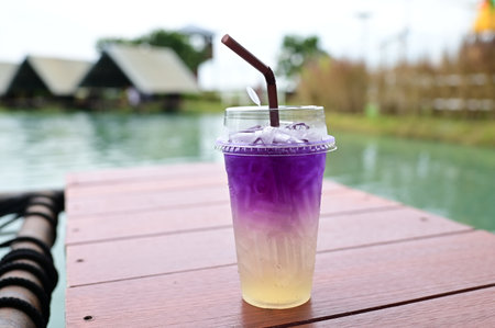 Iced purple tea in plastic cup on wooden table at outdoor swimming poolの写真素材