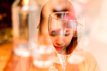 Reflection of a face on a red wine glass in a modern Barの写真素材