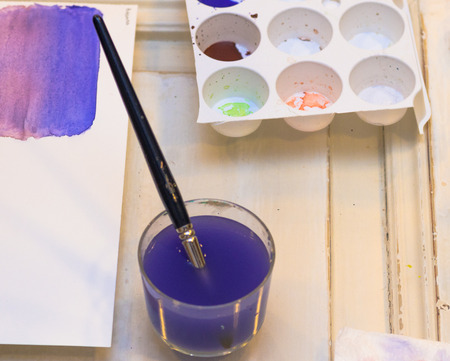 Paint brush in a blue dirty Water on a Tableの写真素材