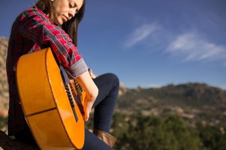Cute Woman playing guitar on a Rock in Madrid