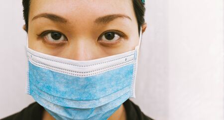 Coronavirus theme. Asian woman  wearing a mask to protect herself from getting infected on a white background.の写真素材