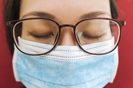 coronavirus theme. Asian woman with glasses wearing a mask to protect herself from getting infectedの写真素材