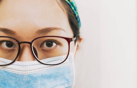 coronavirus theme. Asian woman with glasses wearing a mask to protect herself from getting infectedの写真素材