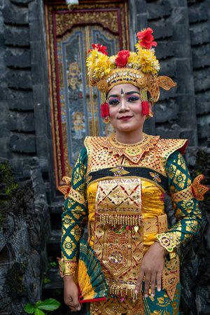 Face portrait of beautiful young woman in traditional Balinese dance costume with golden headdress in Bali templeの写真素材