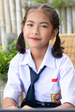 Cute asian girl in school uniform sitting at the table.