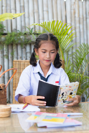 Cute asian thai schoolgirl reading a book at home