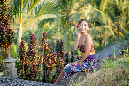 Beautiful Asian woman in traditional Thai dress sitting on the stairs in the garden.の写真素材