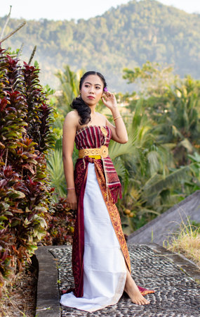 Balinese woman in traditional dress on a background of tropical plants.の写真素材