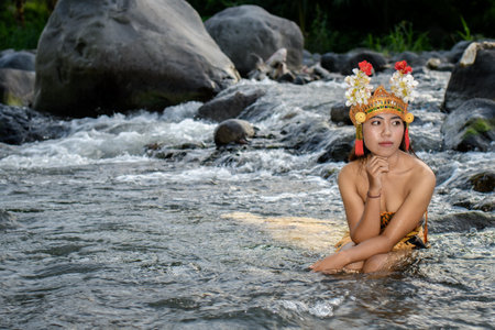 Laughing woman bathing in the river, suit traditional costume and flowers on her head.の写真素材
