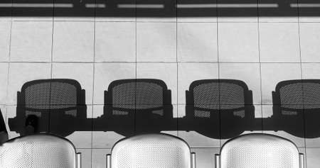 A row of metal chairs with shadows monochromeの写真素材
