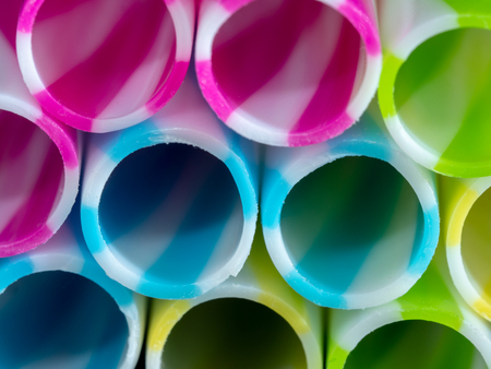 Colourly striped plastic drinking straws, black underground backgroundの写真素材