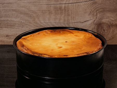 Grandma's cheesecake, freshly baked in a baking dish, against a background of wood