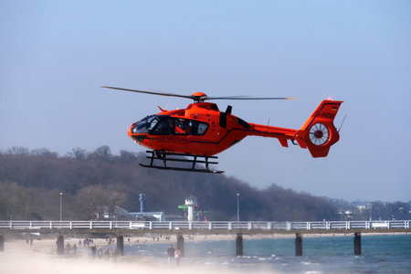 Timmendorfer Strand, Germany - March 28, 2020: Orange rescue helicopter that has landed on the beach to quickly bring medical personnel to a place.のeditorial素材