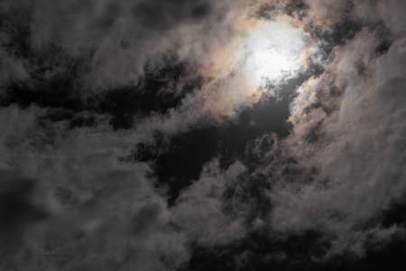 Night sky with moon behind clouds.