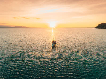 Traditional wooden boat with beautiful sunset at the sea. Perfect time for fishingの写真素材