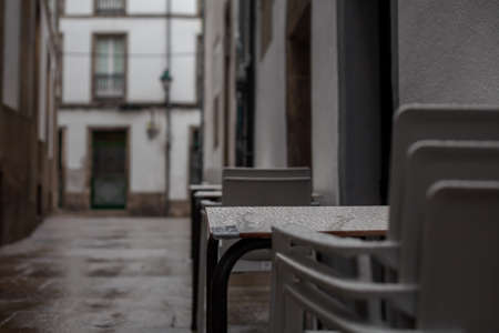 Stacked plastic chairs from a restaurant outisde in an old rustic rainy street of Santiago de...