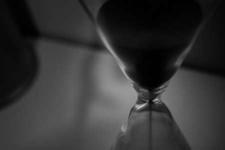 Close up hourglass black & white background. Moody time sand background.
