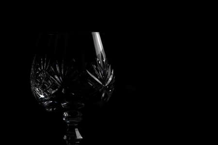 Empty crystal brandy glass on a dark black background in dramatic lighting. Isolated fine dining drinking glass bar & restaurantの写真素材