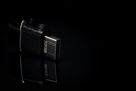 Worn used 32gb memory stick placed on its side on a reflective black surface in dramatic lighting....
