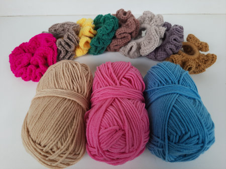 Colored balls of crochet thread, scissors and a needle on a white background