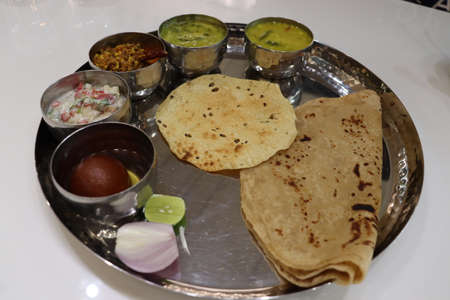 North Indian thali consisting of multiple bowls full of curries, and dessert with salad. Indian food culture in modern restaurant.の写真素材