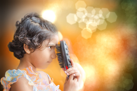 happy fashion girl playing with hair brush on abstract colorful backgroundの写真素材
