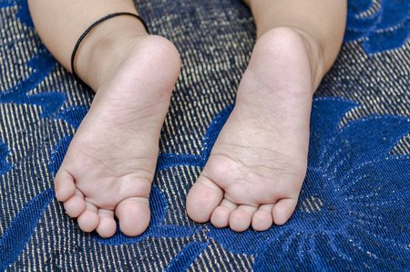foot of infant baby boy on blue abstract backgroundの写真素材