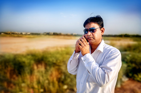 young businessman talking secretly on smart phone at country sideの写真素材