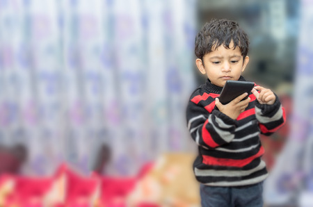 boy child playing with mobile phone in living room homeの写真素材