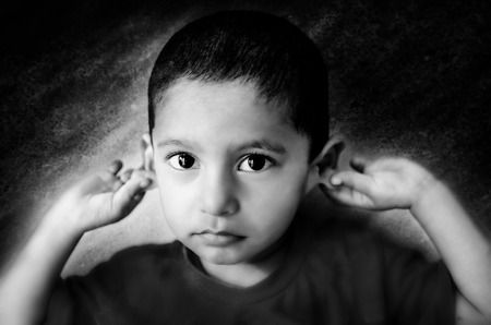 little child saying sorry child holding ears monochrome portrait shot with nikon d-5100 processed in adobe lightroom and photoshopの写真素材