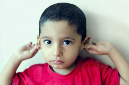 little child saying sorry child holding ears    の写真素材