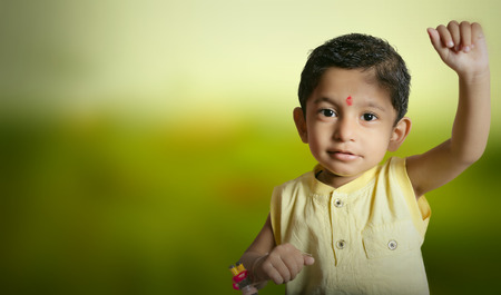Indian asian superhero boy child raising hand for flight wearing tilak on forehead in yellow ben collor shirtの写真素材