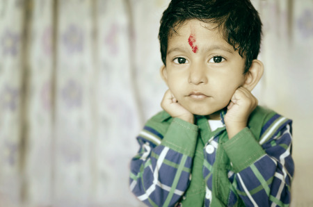 little asian indian child posing for camera looking into camera wearing shirtの写真素材