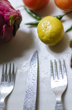 Lime tomatoes cabbage dragon fruit vegetables and fork knife top viewの写真素材