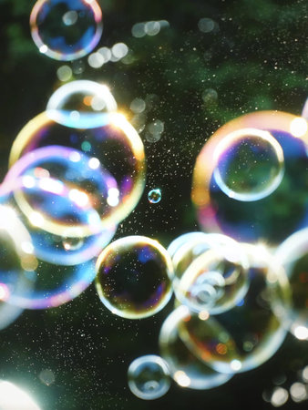 Soap bubbles with bokeh effect on a dark background.