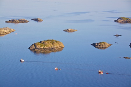 Three fishing boats sailing out to the open sea near Henningsvaer, Norwayの写真素材