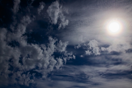 Dark blue sky with scattered clouds and sunの写真素材