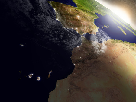 Morocco with surrounding region during sunrise as seen from Earth's orbit in space. 3D illustration with highly detailed realistic planet surface, clouds and city lights.の写真素材