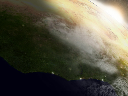 Ivory Coast, Ghana and Burkina Faso with surrounding region during sunrise as seen from Earth's orbit. 3D illustration with highly detailed realistic planet surface, clouds and city lights.の写真素材