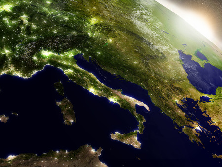 Italy with surrounding region during sunrise as seen from Earth's orbit in space. 3D illustration with highly detailed realistic planet surface, clouds and city lights.の写真素材