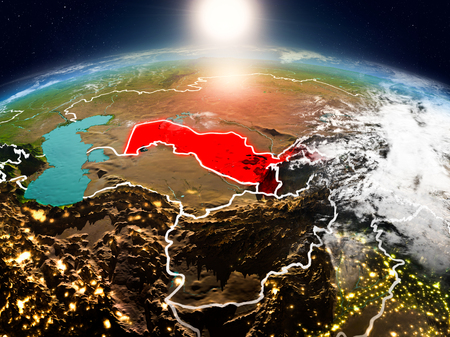 Sunrise above Uzbekistan highlighted in red on model of planet Earth in space with visible country borders. 3D illustration.の写真素材