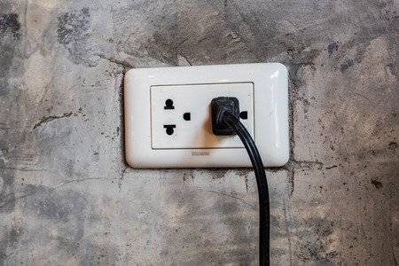 Black and white plug with cement wall at cafe shop