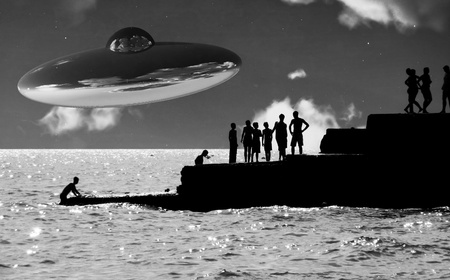 A UFO over a coastline with some silhouetted people. の写真素材